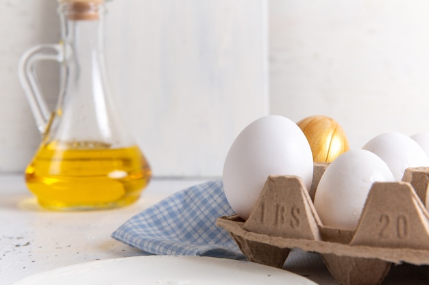 Front close view white whole eggs with golden one on the white wall