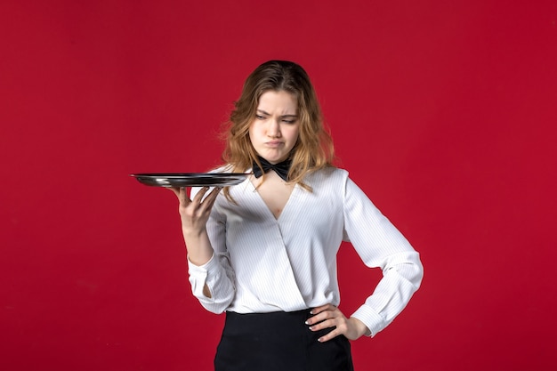 Free photo front close view of young concerned female server butterfly on the neck and holding tray on red background