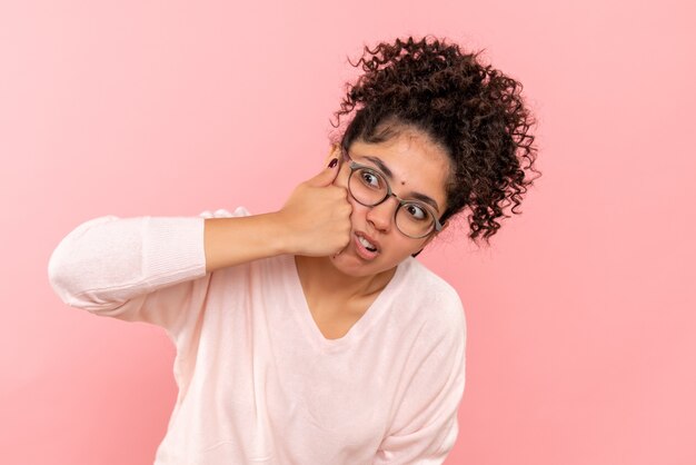 Front close view of young female beating herself on pink