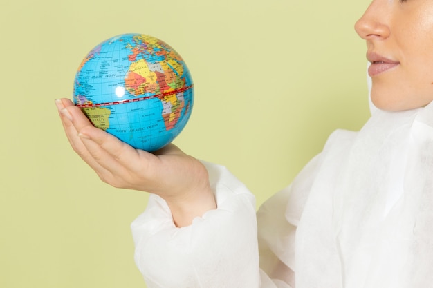 Free Photo front close view young female in white special suit and yellow helmet holding little earth globe on green