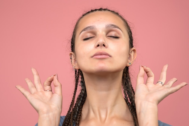 Front close view of young girl meditating on pink