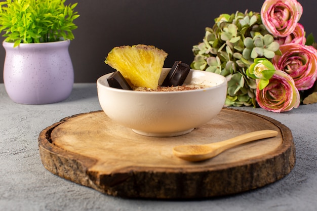 Free Photo a front closed up view choco dessert brown with pineapple slice choco bars flowers on the brown wooden desk and grey