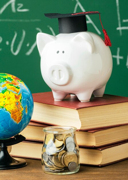 Front view of academic cap on piggy bank and stack of books