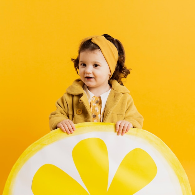 Front view of adorable child posing with lemon slice decoration