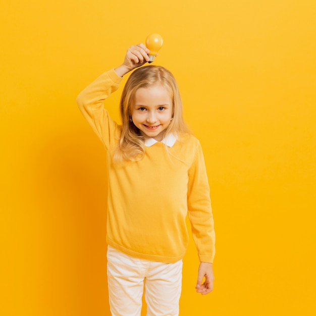 Free photo front view of adorable girl posing while holding yellow light bulb