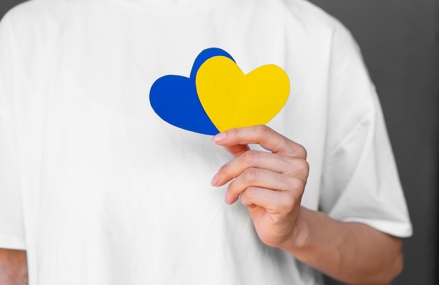 Front view adult holding yellow and blue hearts