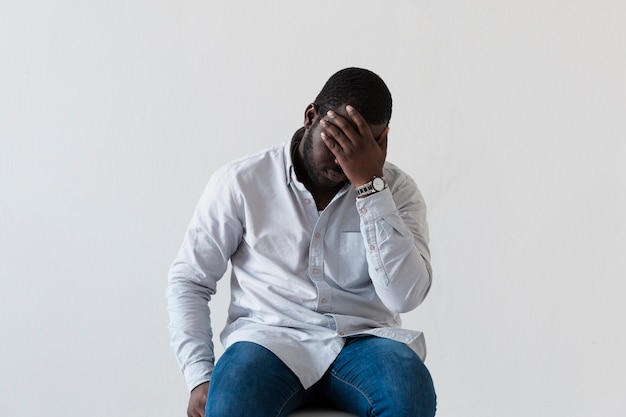 Front view afro-american man covering his face