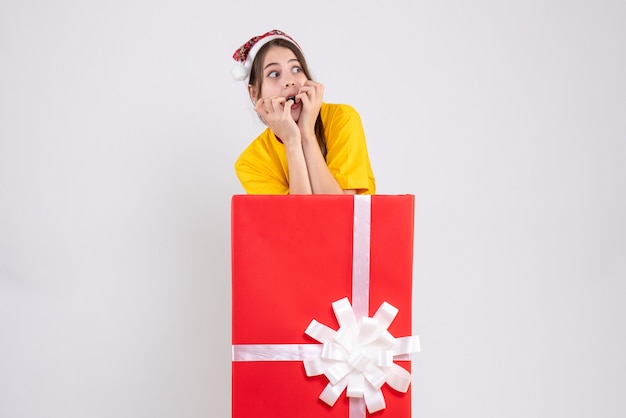 Free Photo front view agitated girl with santa hat standing behind big xmas gift