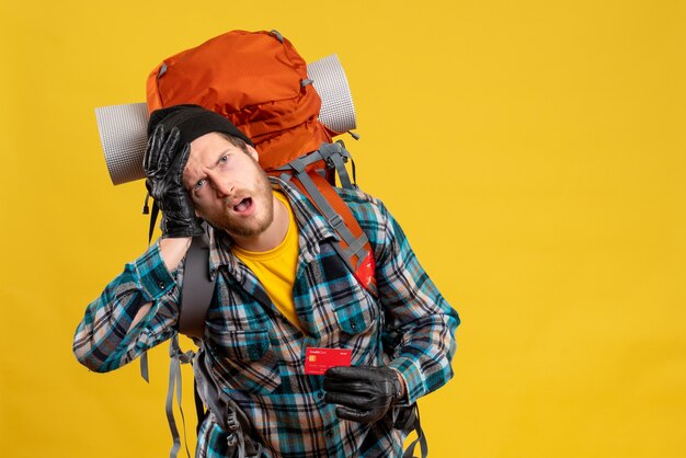 Front view of agitated young man with backpacker holding discount card