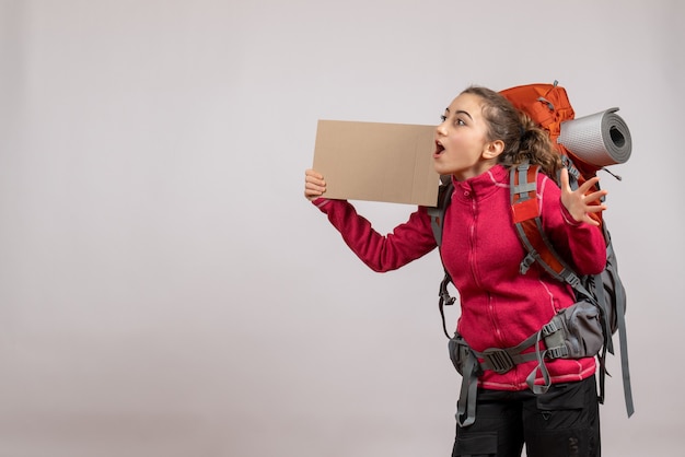 Free Photo front view of amazed pretty woman with big backpack holding up cardboard