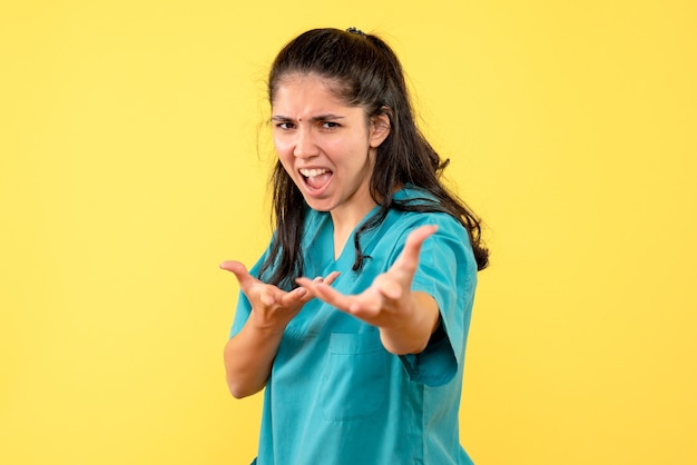 Free Photo front view angry female doctor in uniform standing on yellow isolated background