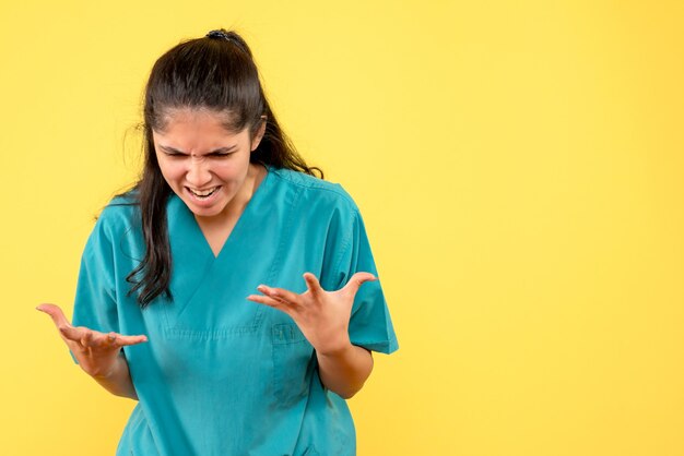 Front view angry female doctor in uniform standing on yellow isolated background