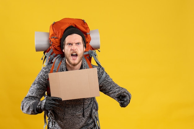 Free photo front view of angry male hitchhiker with leather gloves and backpack holding blank cardboard