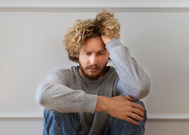 Free photo front view anxious man sitting on floor