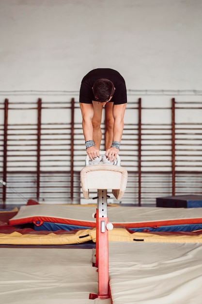 Front view athletic man exercising on pommel horse