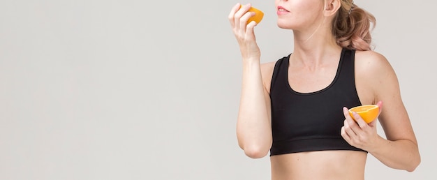 Free photo front view of athletic woman enjoying an orange with copy space