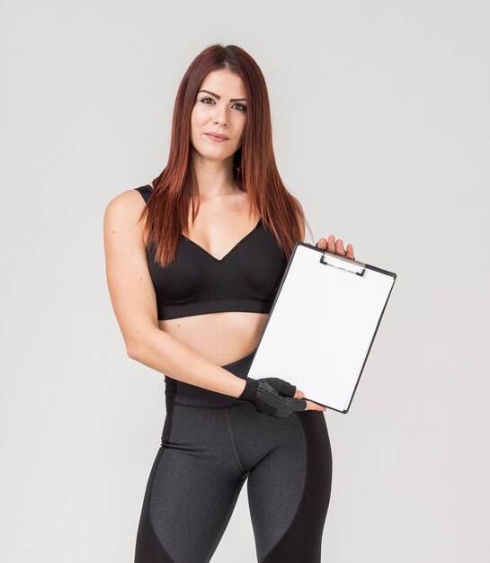 Front view of athletic woman holding notepad