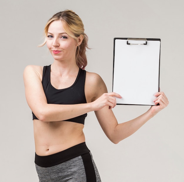 Free photo front view of athletic woman smiling and holding notepad