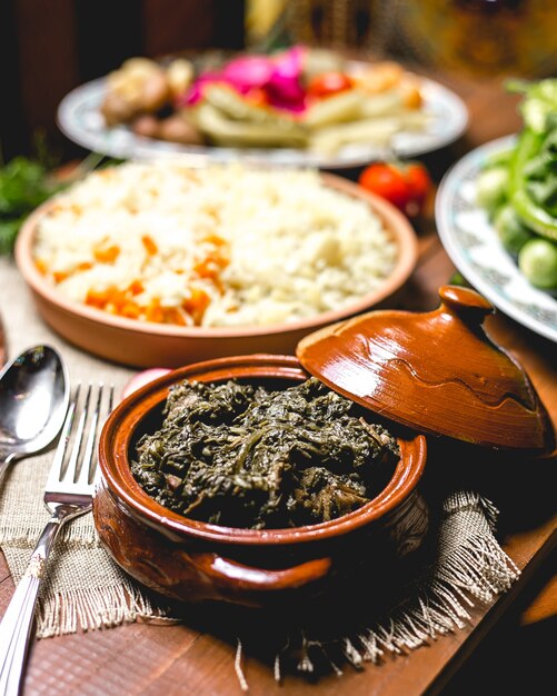 Front view baked meat with greens in a pot with boiled rice