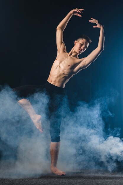 Front view of ballerino in tights posing in smoke