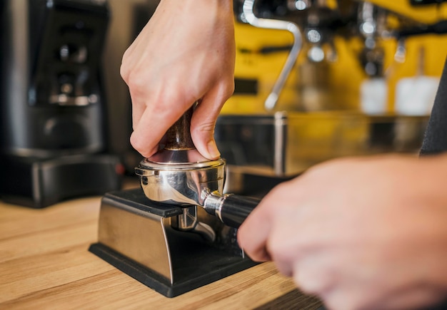 Front view of barista filling cup with coffee for machine