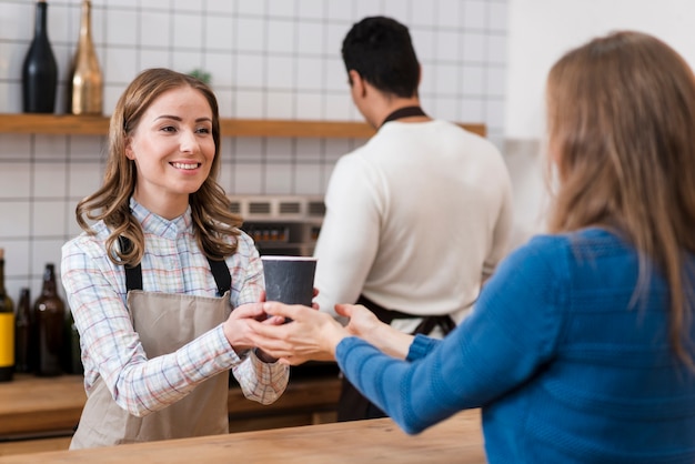 Front view of barista giving coffe to client