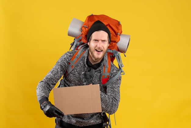 Free photo front view of bearded male hitchhiker with leather gloves and backpack holding up blank cardboard