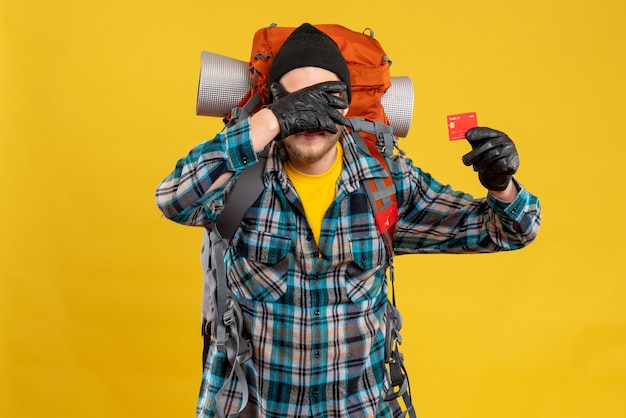 Free photo front view of bearded young man with backpacker holding credit card covering his face with hand