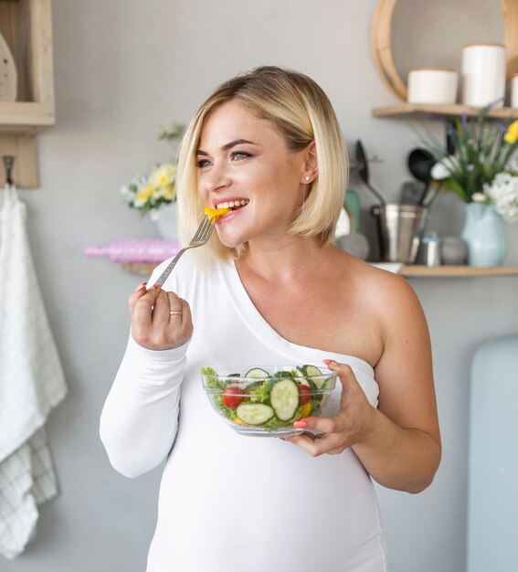 Front view beautiful pregnant woman eating salad