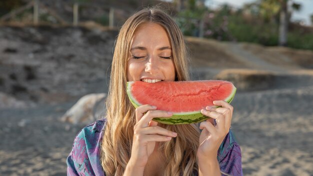 Front view of beautiful woman eating watermelon