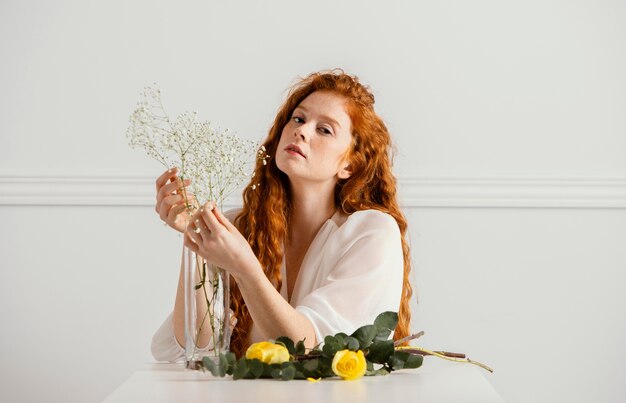 Front view of beautiful woman posing with spring flowers on the table