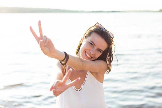 Free photo front view beautiful woman showing the peace sign