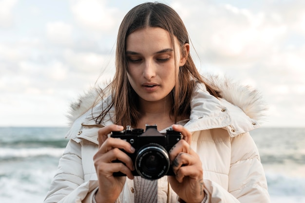 Free photo front view of beautiful woman with camera at the beach