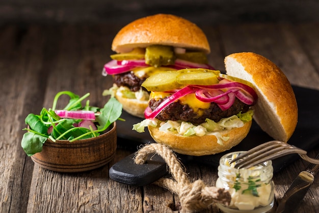 Free photo front view beef burgers with pickles and red onions on cutting board