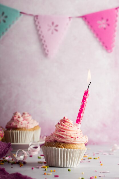 Front view of birthday cupcake with garland and lit candle