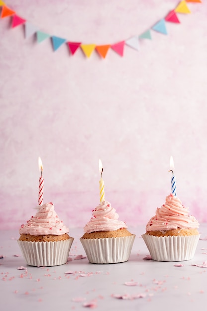 Free photo front view of birthday cupcakes with garland and lit candles