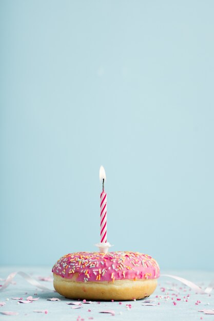 Front view of birthday doughnut with lit candle and copy space