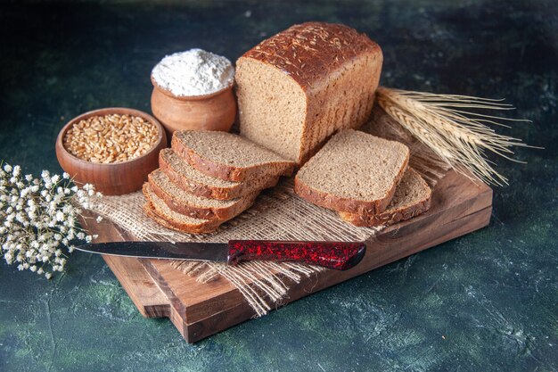 Front view of black bread slices on nude color towel spikes flower on cutting boards on mixed colors background