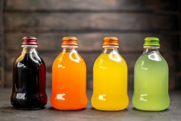 Front view black orange yellow and green fruit juice in bottles