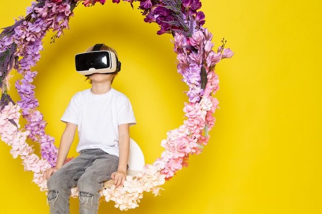 Free Photo a front view blonde boy playing vr on the flower made stand on the yellow desk