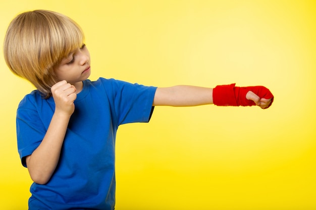 Free Photo a front view blonde boy posing boxing in blue t-shirt on the yellow wall