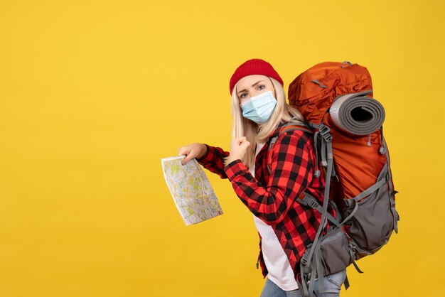 Front view blonde girl with her red backpack holding map