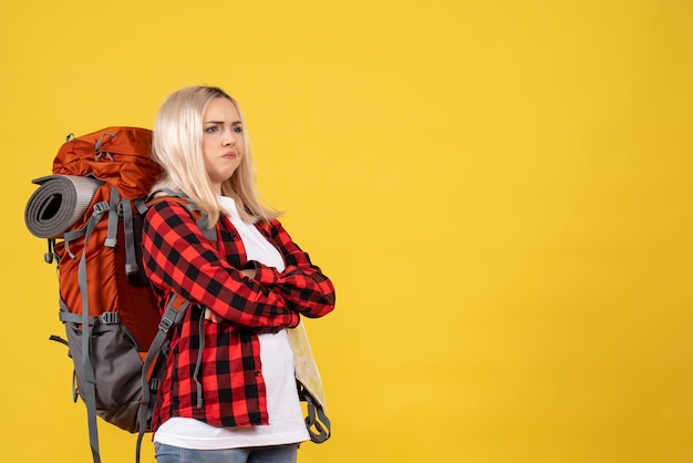 Free photo front view blonde traveler woman with her backpack crossing hands standing on yellow wall