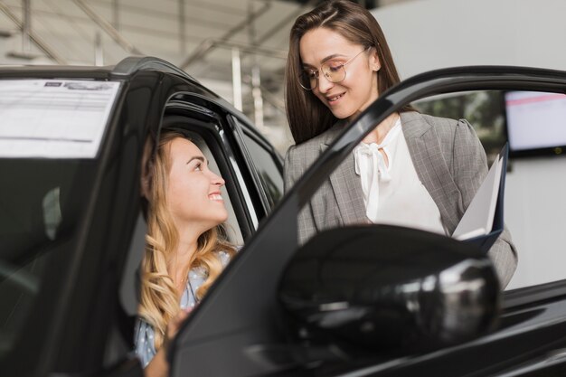 Front view blonde woman talking with car dealer