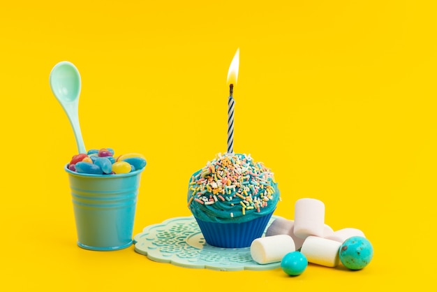 A front view blue cake with candle along with marshmallows and marmalades on yellow, sweet sugar biscuit