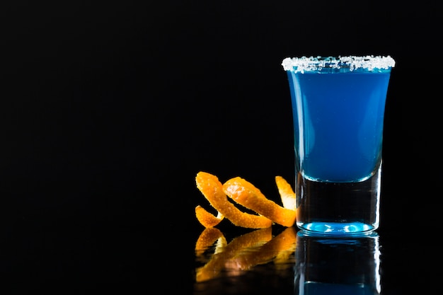 Free photo front view of blue cocktail in shot glass with orange peel