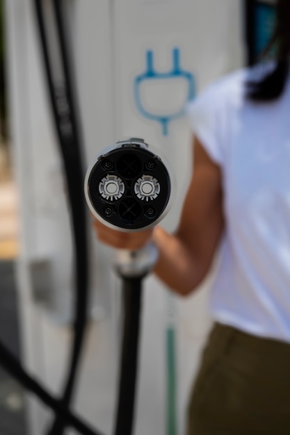 Free photo front view blurry woman holding car charger