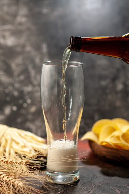 Front view bottle of bear pouring into the glass on light desk