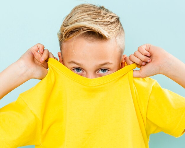 Front view boy covering his face with t-shirt