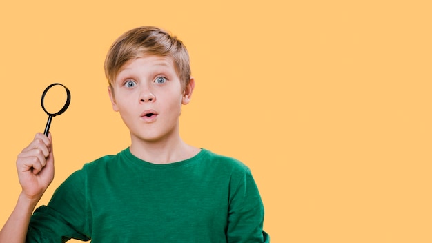 Front view of boy holding magnifying glass with copy space